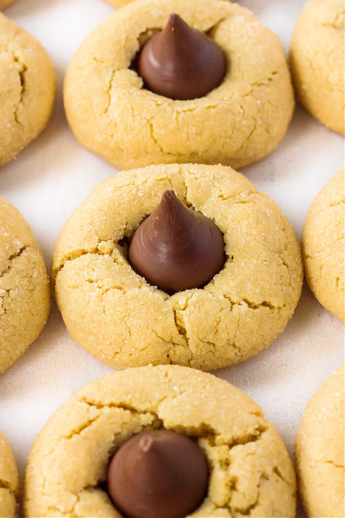 Peanut Butter Blossoms (Hershey Kiss Cookies) are pillowy soft peanut butter cookies rolled in sugar & topped with a Hershey's Kiss. HOMEMADE PEANUT BUTTER BLOSSOMS