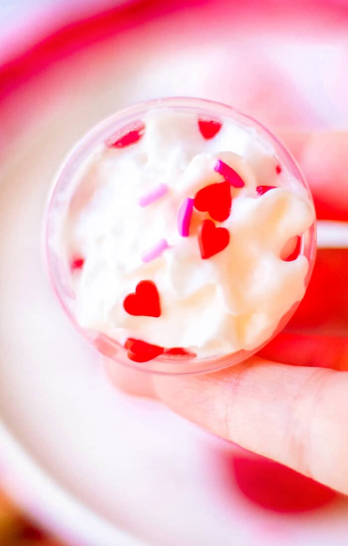 Valentine’s jello shots are a festive layered shot of raspberry and strawberry jello topped with whipped cream & sprinkles! RED HOLIDAY JELLO SHOTS