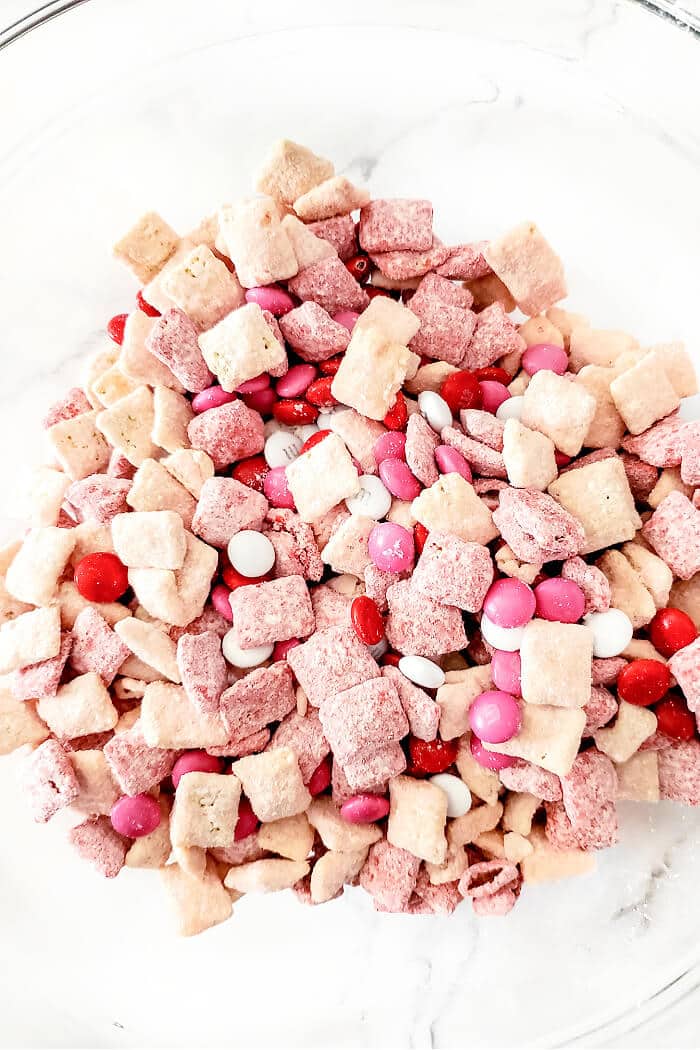 Strawberry muddy buddies are a delicious snack made with Chex, white and red chocolate melts, strawberry cake mix, powdered sugar and M&MS. STRAWBERRY PUPPY CHOW