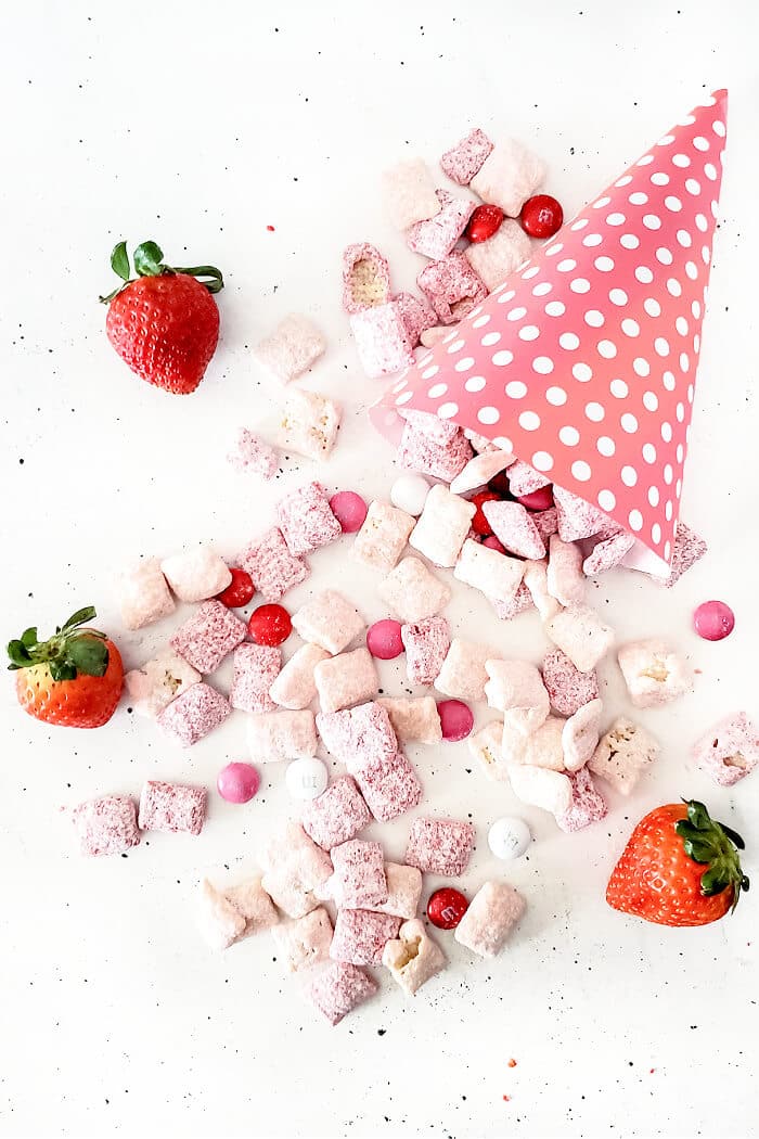 Strawberry muddy buddies are a delicious snack made with Chex, white and red chocolate melts, strawberry cake mix, powdered sugar and M&MS. STRAWBERRY PUPPY CHOW RECIPE
