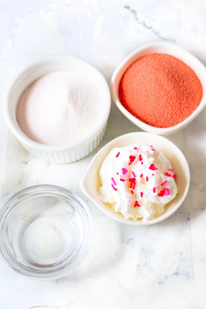 Valentine’s jello shots are a festive layered shot of raspberry and strawberry jello topped with whipped cream & sprinkles! VALENTINE'S JELLO SHOTS INGREDIENTS