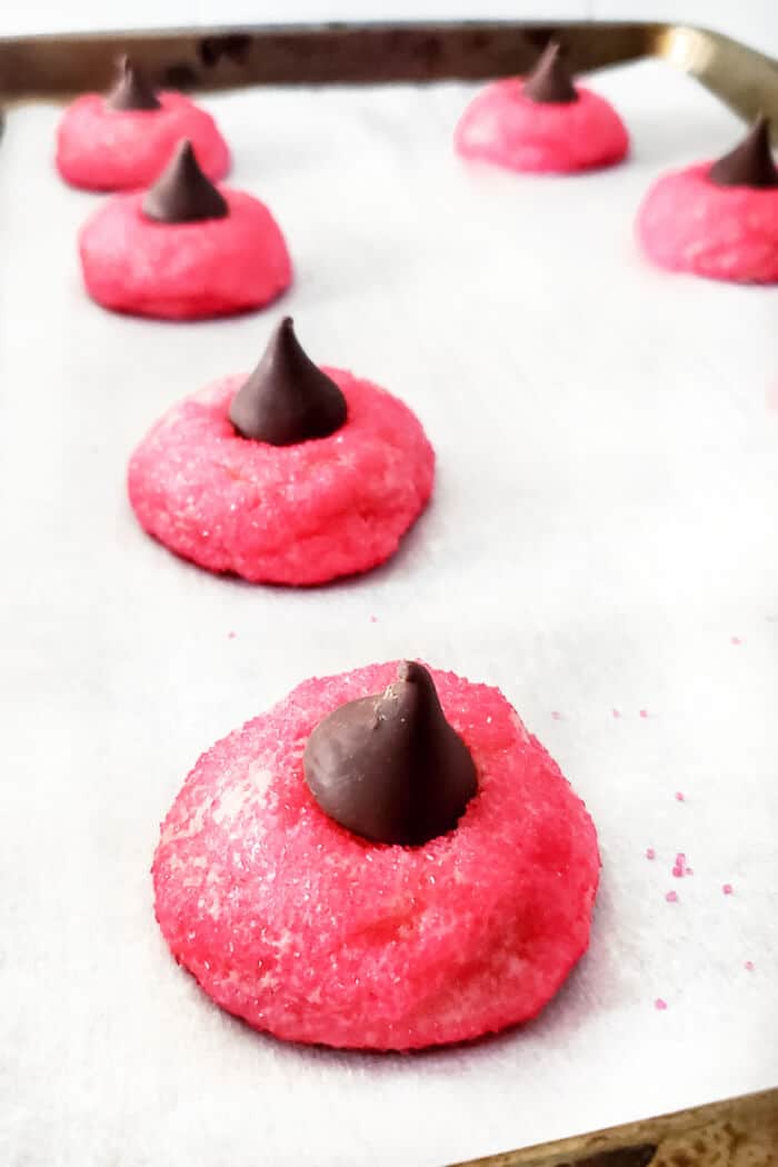 Strawberry kiss cookies are a fun spin on the original made with strawberry cake mix, cream cheese, sugar, and a delicious chocolate kiss! STRAWBERRY KISS BLOSSOM COOKIES