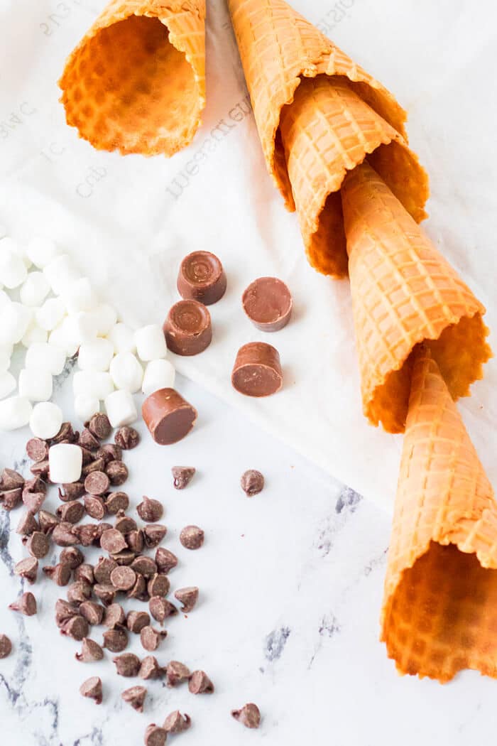Campfire cones are a fun treat to make for your next get together made with waffle cones, mini marshmallows, and chocolate candy. CAMPFIRE CONES INGREDIENTS
